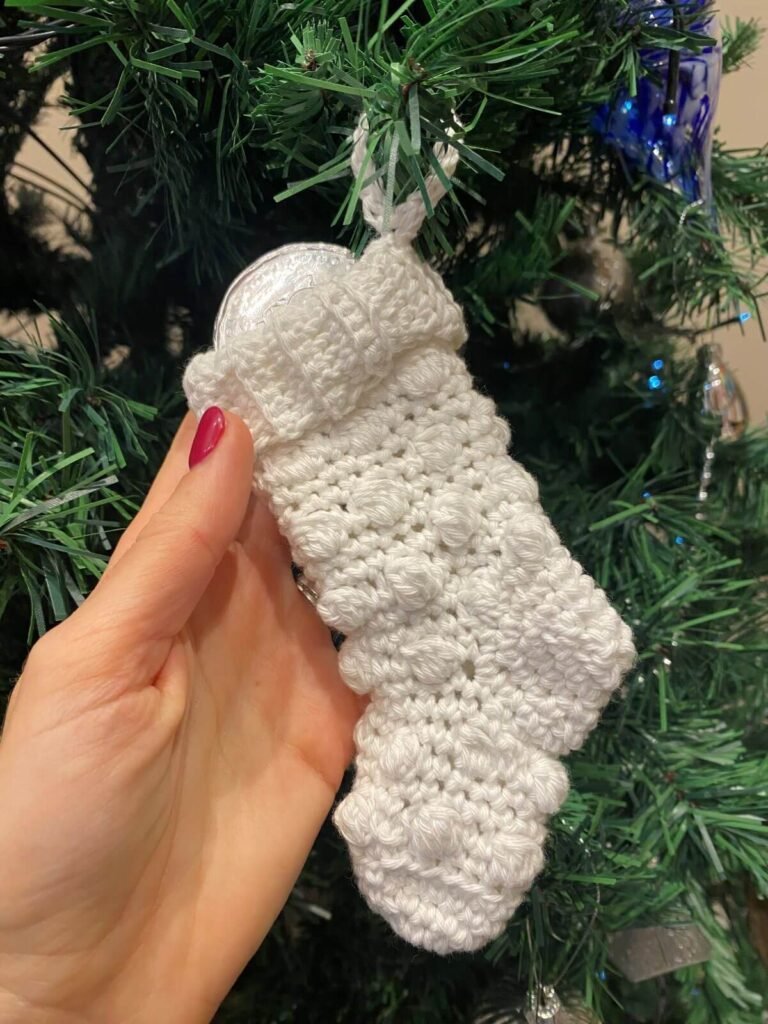 hand holding a white stocking with a chocolate coin in it