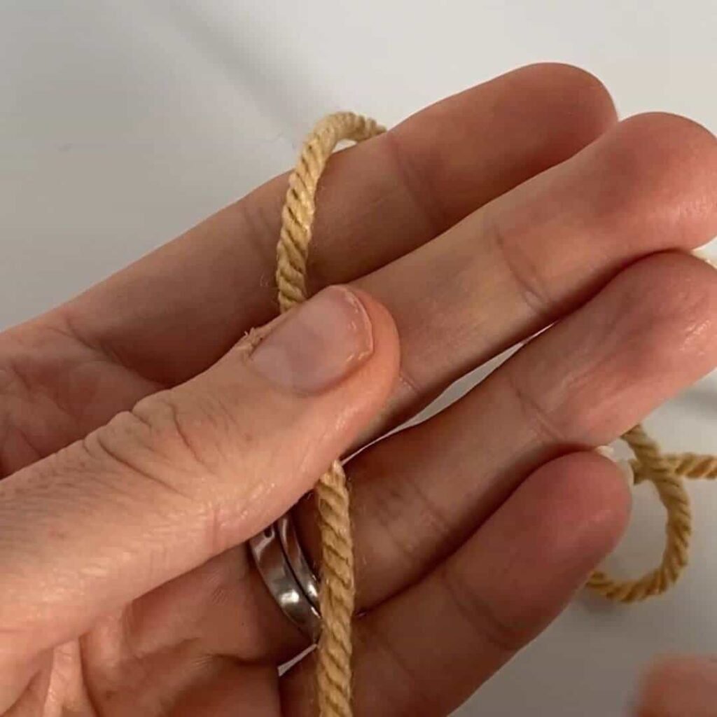 A hand holding a piece of yarn, ready to demonstrate a crochet slipknot tutorial