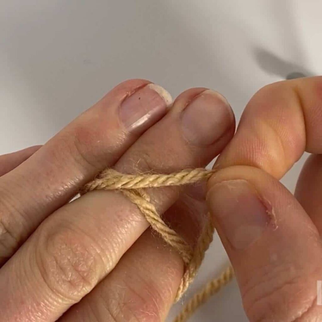 image showing yarn wrapped twice around 2 fingers, and one loop being pulled over the other