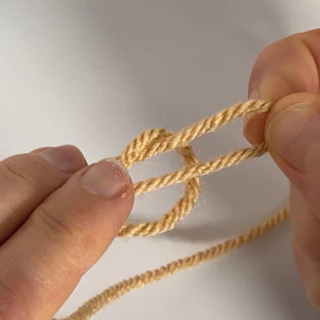 hands pulling a loop in the yarn to make a crochet slipknot