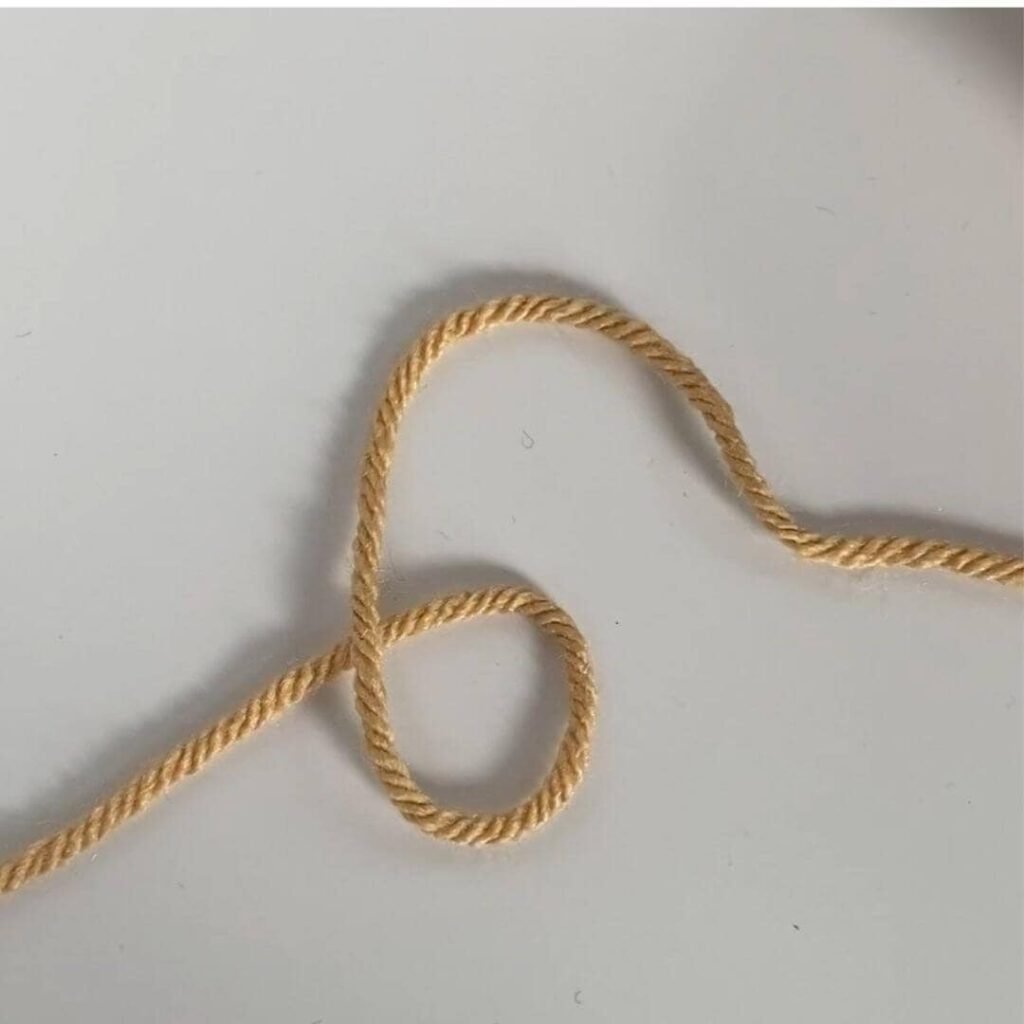 yarn laid out on the table in the shape of a 6, ready to make a slipknot