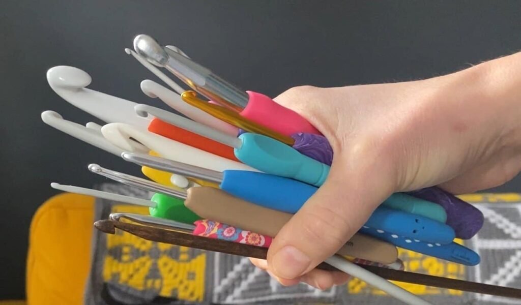 a hand holding lots of crochet hooks