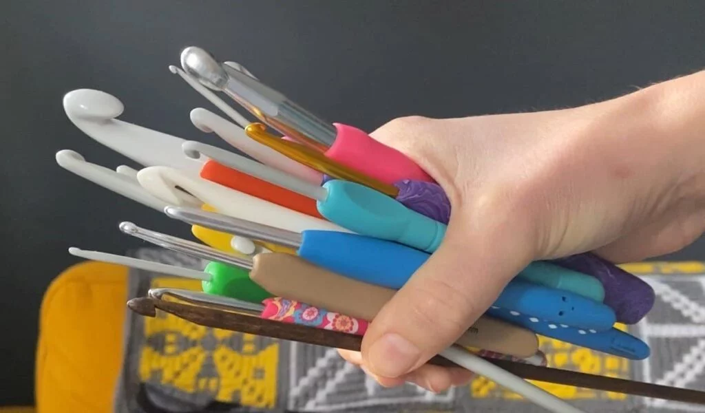 a hand holding lots of crochet hooks