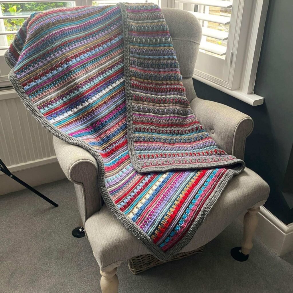 A stripy crocheted blanket over a chair
