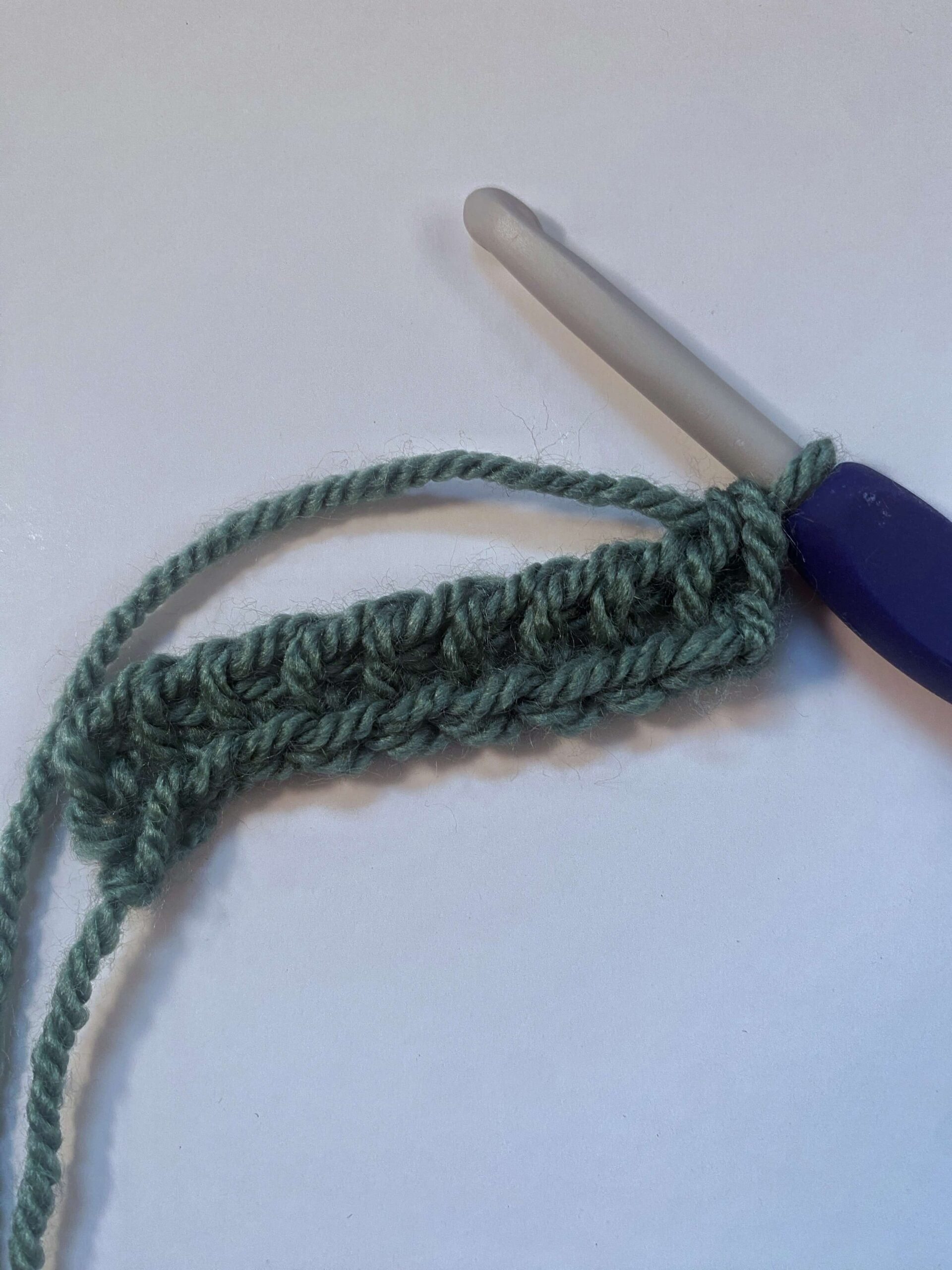 A crochet hook and crocheted fabric showing the Return pass of Tunisian Crochet