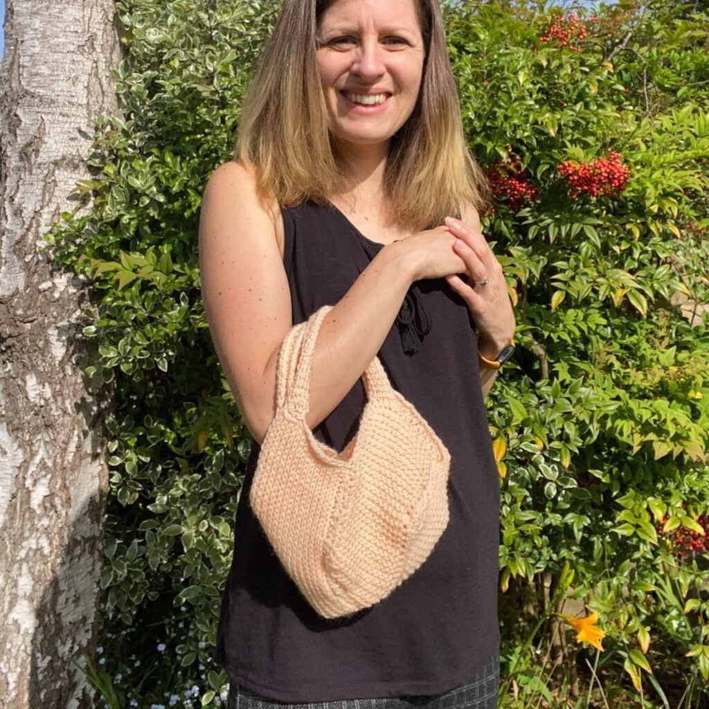 Small Tunisian Crochet bag held by a woman wearing a black vest top