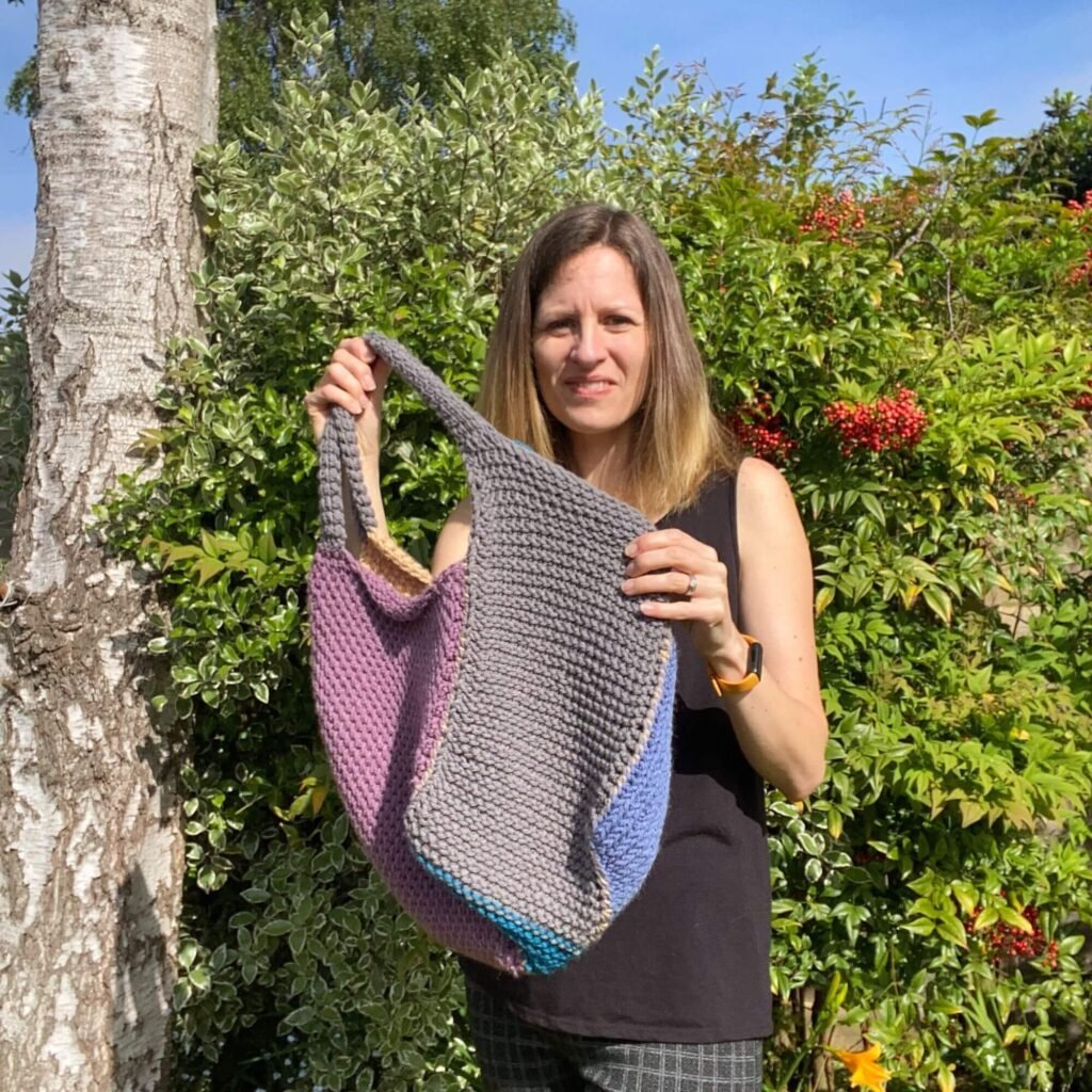 A lady holding up a patchwork crocheted bag