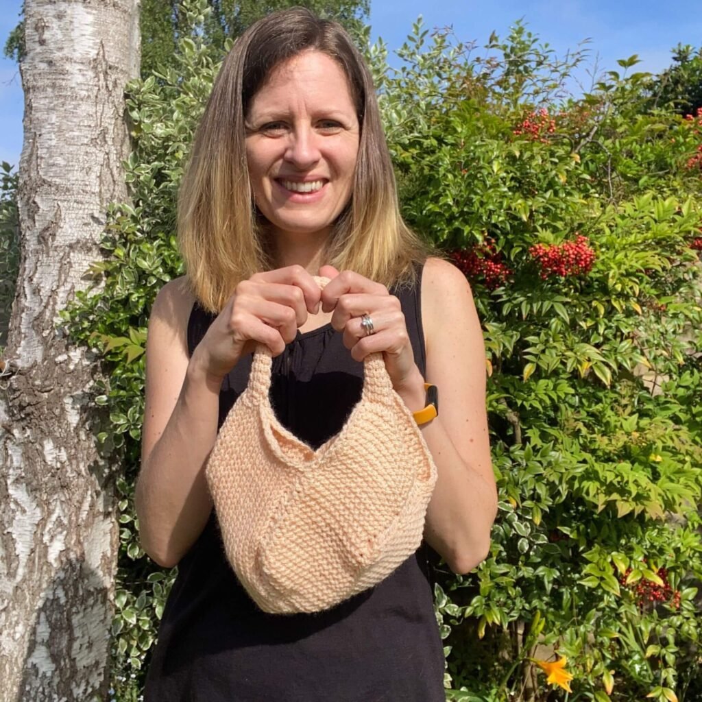 A woman holding a small crocheted tote bag