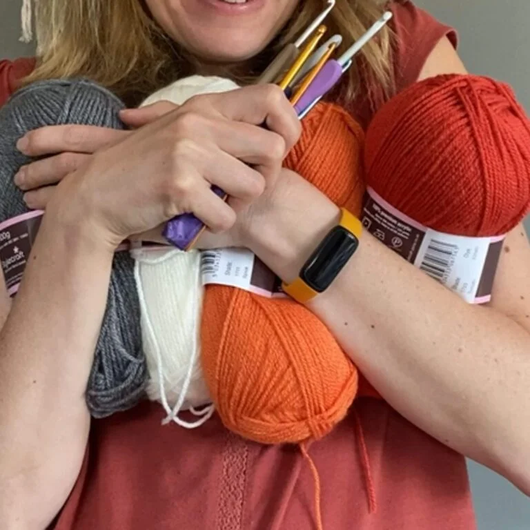 Arms holding hooks and yarn
