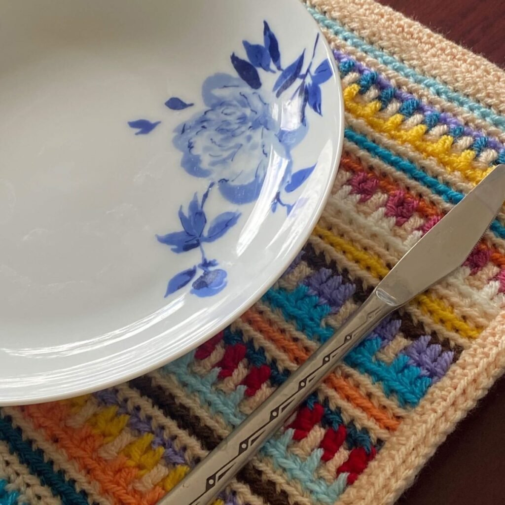 A plate and knife sitting on a crocheted placemat