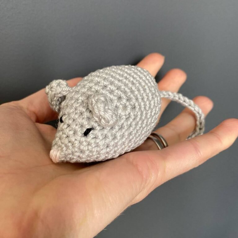 A crocheted grey mouse being held in a hand