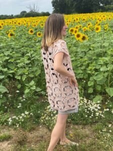 A lady with her back turned wearing a beige crochet lace cardigan