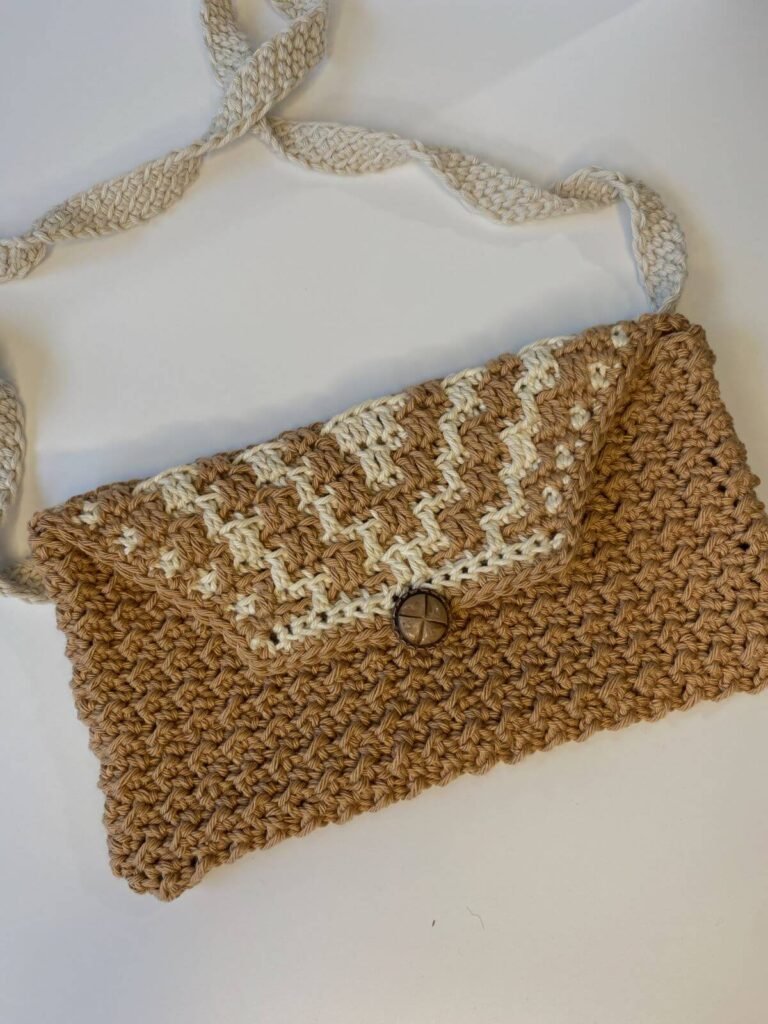 A small brown and beige crochet handbag with a brown button and cream strap