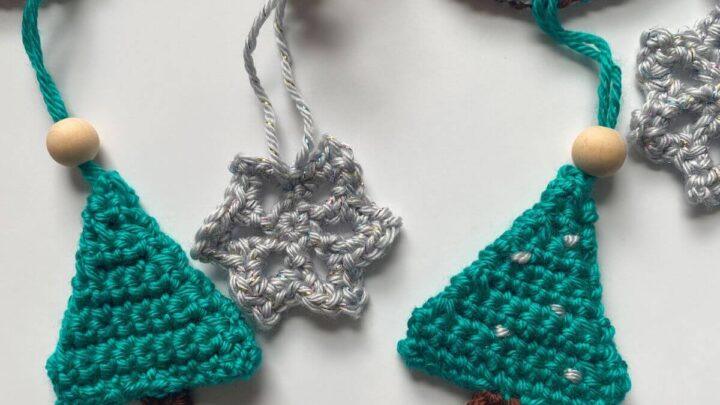 crochet green trees and silver snowflakes hang on a garland with wooden beads