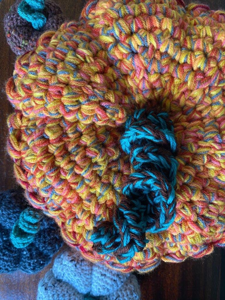 close up of a large orange crochet pumpkin with green and brown stem