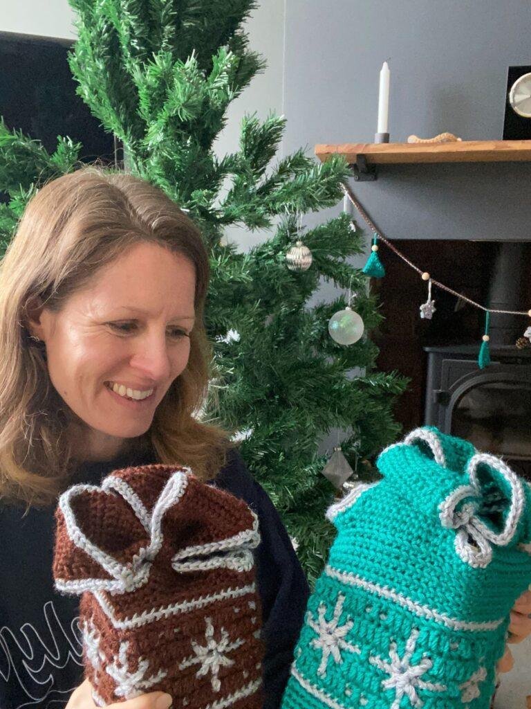 A lady looking at 2 crochet gift wraps that look like presents with snowflakes on them