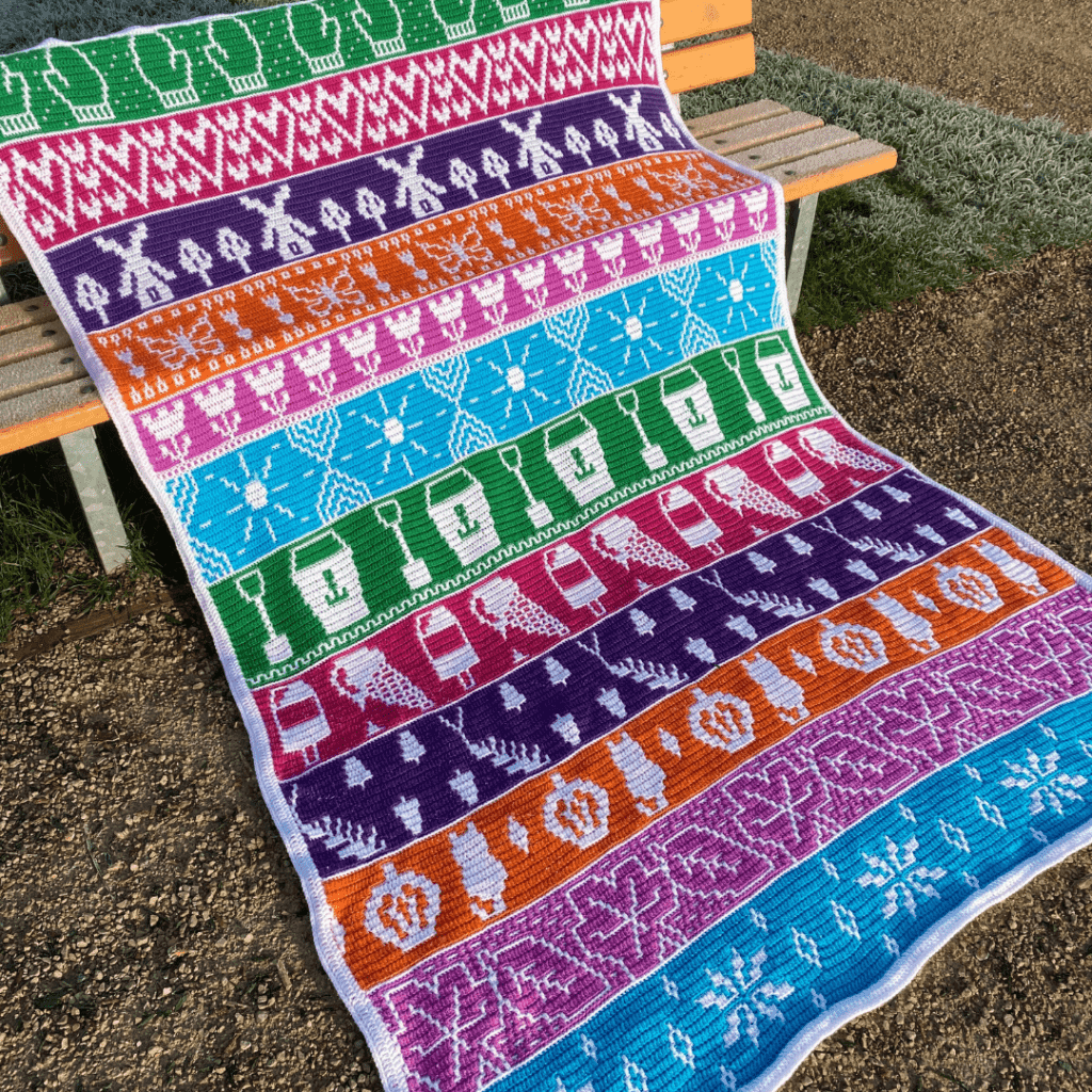 A crochet blanket is laid on a bench - it is the months of the year blanket cal