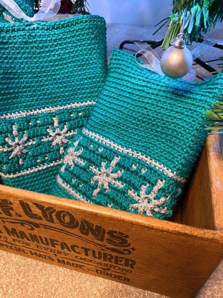 2 crochet green book covers with books inside, sit in a brown Lyons box