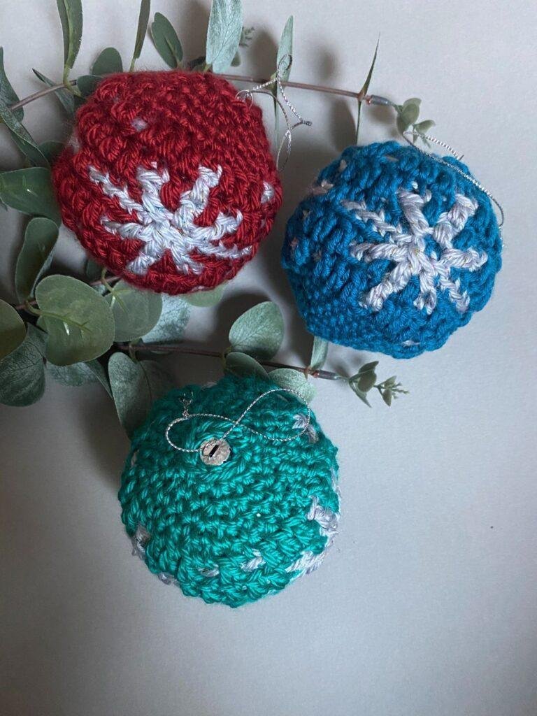 3 crochet baubles with snowflakes on some greenery
