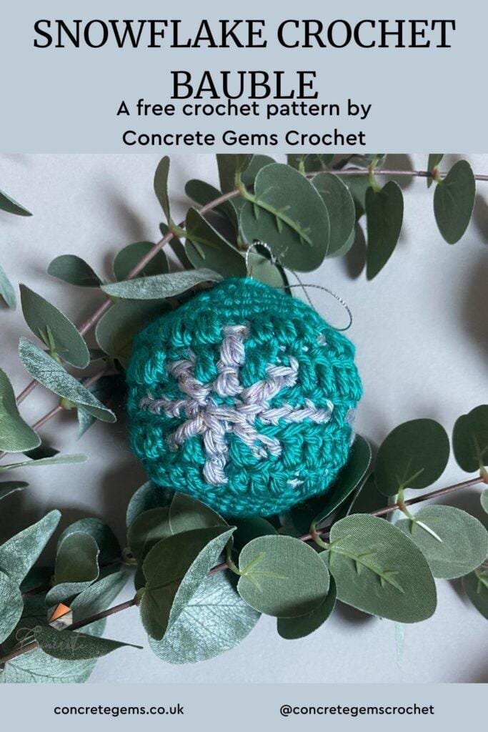 A pin image showing a green crochet bauble with snowflake motif amongst some greenery