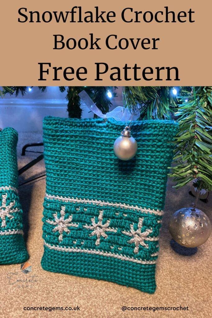 A crochet book cover propped up by a Christmas tree, with green and silver snowflakes