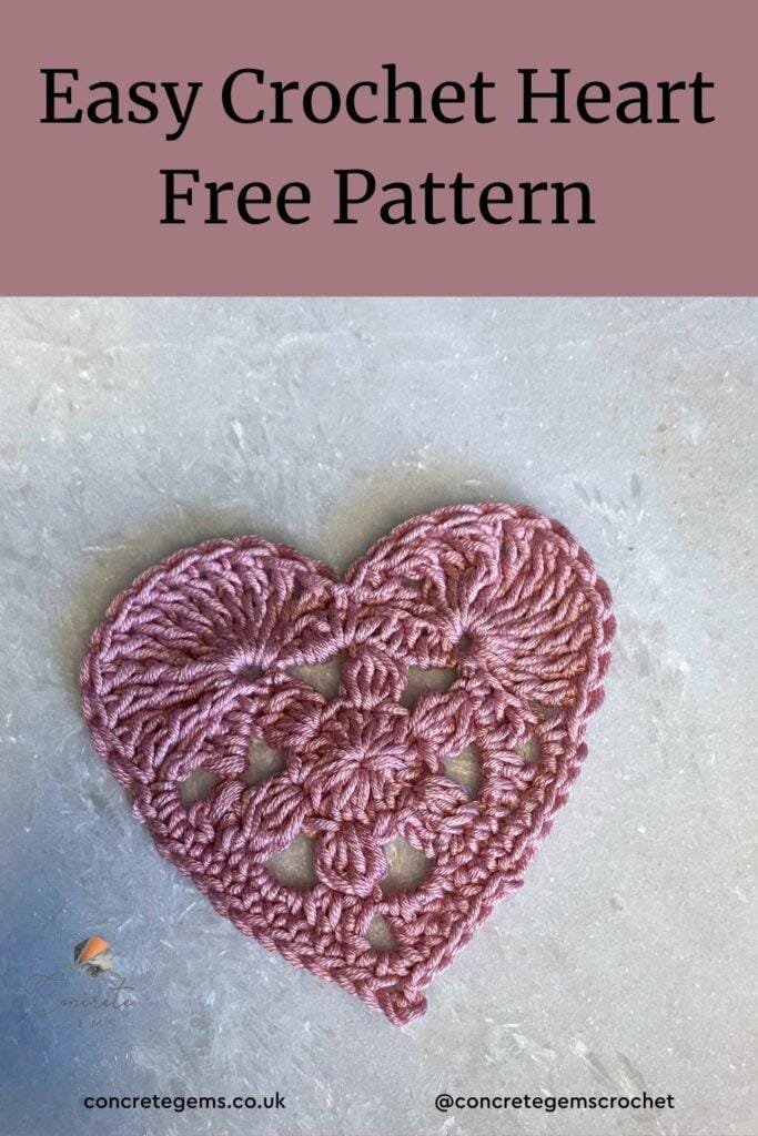 A pink crochet love heart on a marble background as a pin image