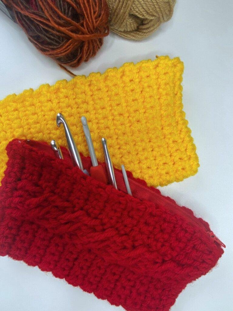 A red and a yellow crochet hook case with a cable detail on the front