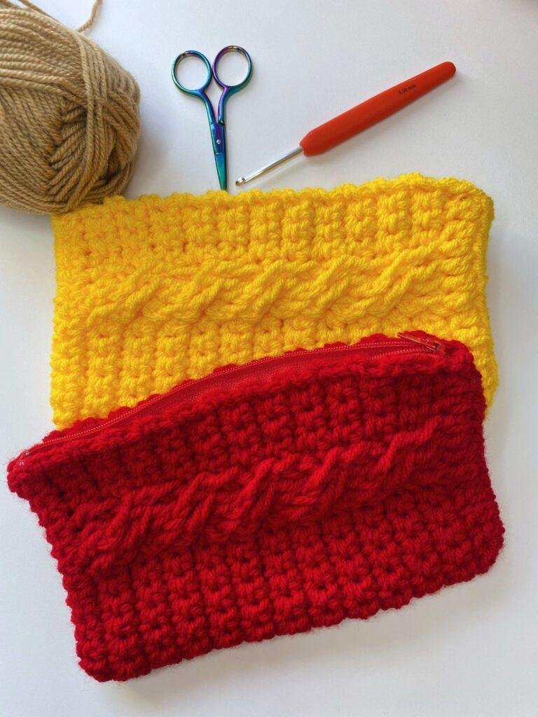 a red and yellow crochet hook case are laid on a white table with scissors hook and yarn around