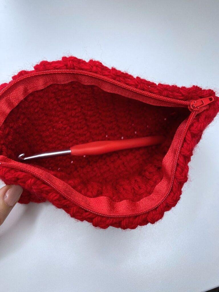 An open red crochet pouch shows a crochet hook inside