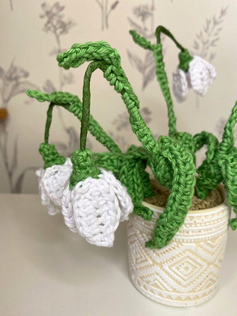 A close up of a pot of crochet snowdrops focussing on one snowdrop hanging down