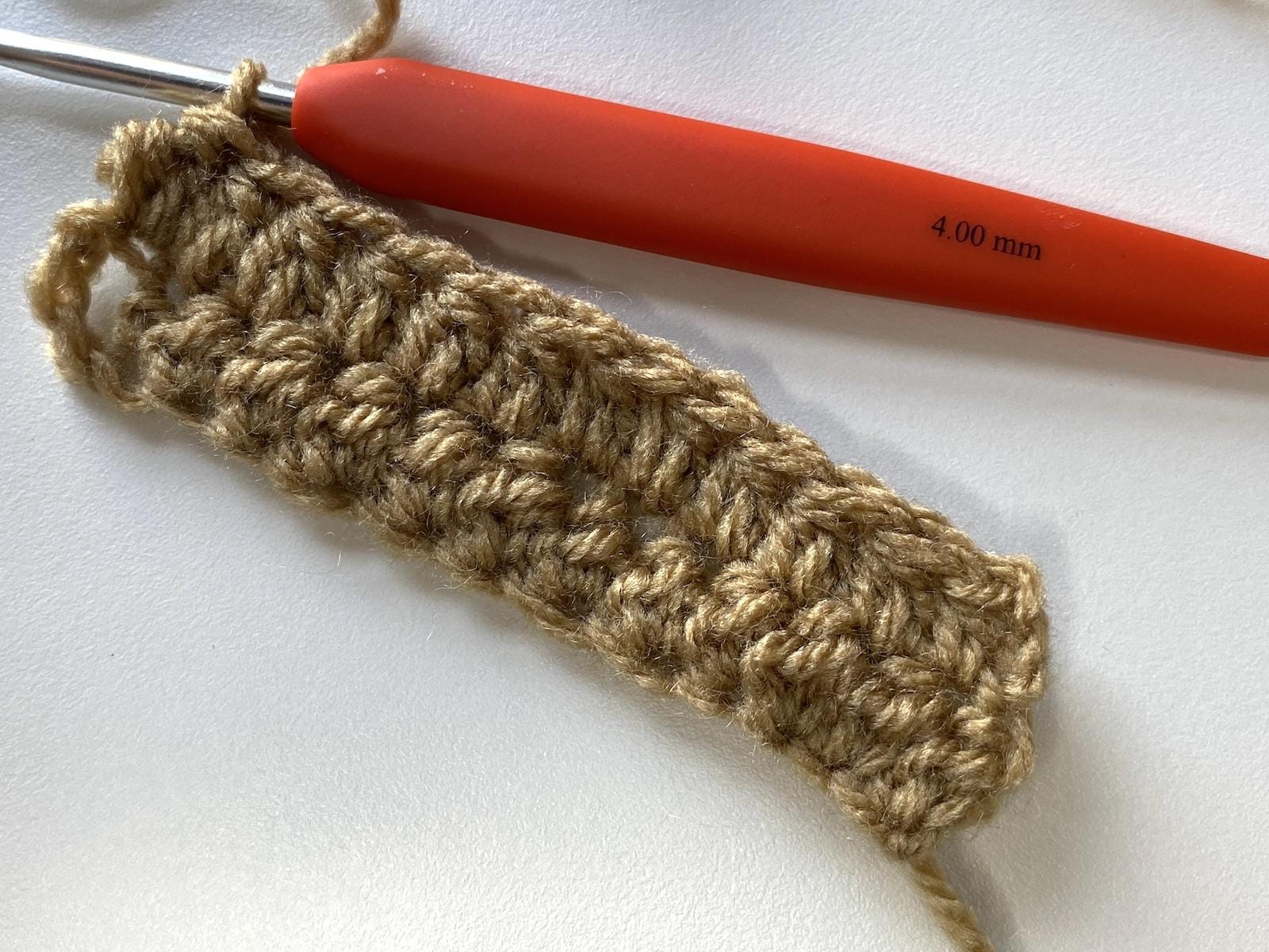 a small sample of crochet pique stitch and an orange crochet hook