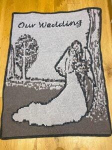 A crochet wedding blanket in greys on a wooden background