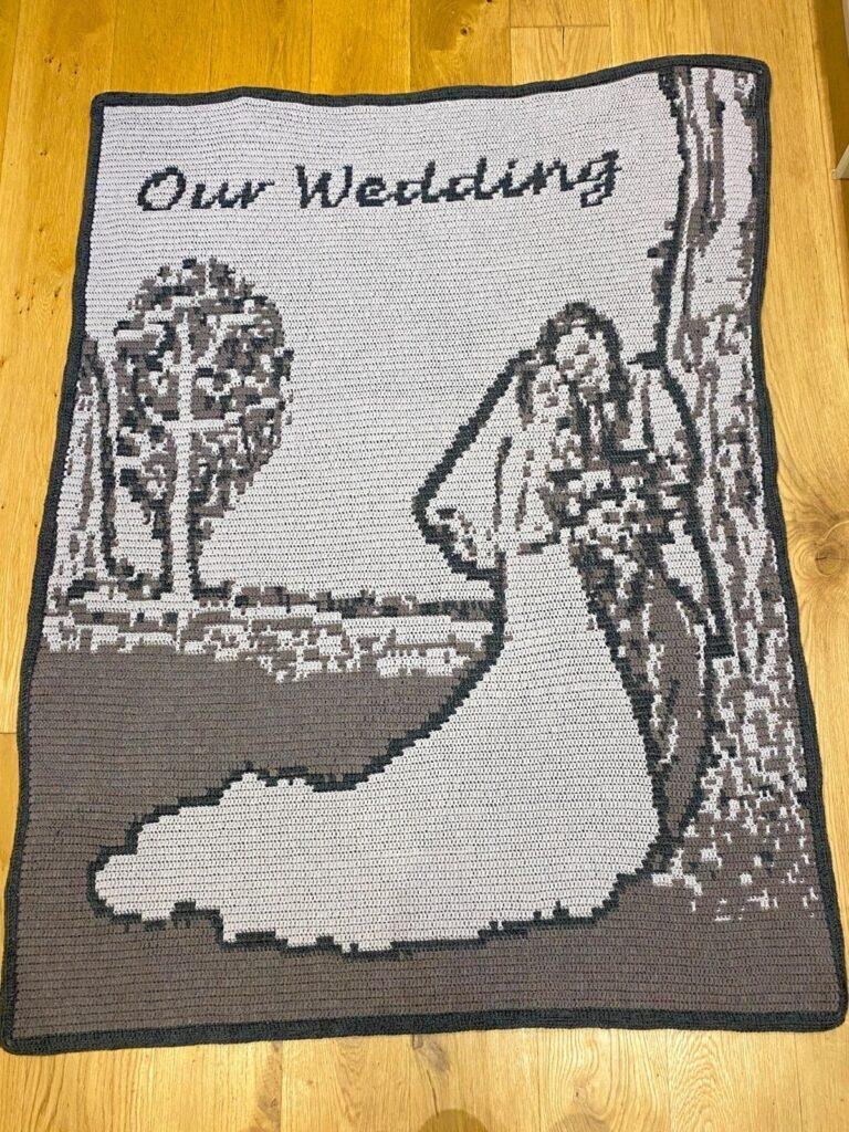 A crochet wedding blanket in greys on a wooden background
