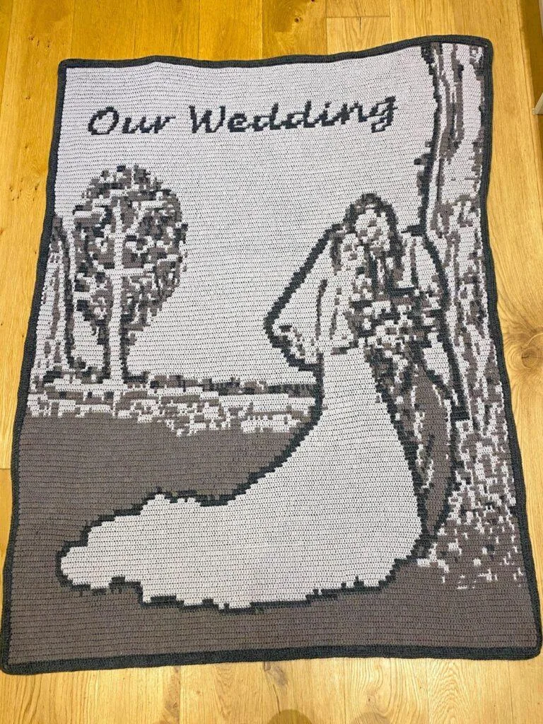 A crochet wedding blanket in greys on a wooden background