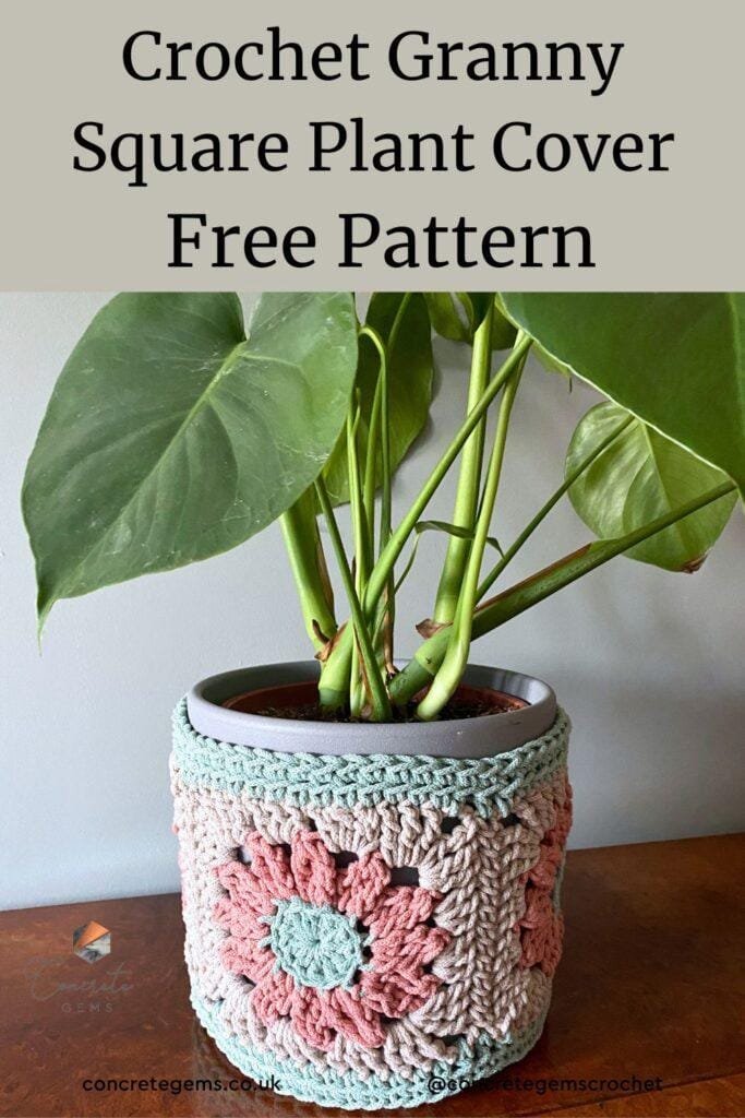 a grey, pink and green plant pot cover covers a plant pot with a plant in it