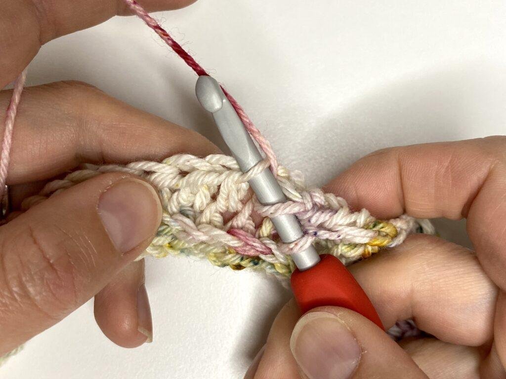 Image of a crochet hook being inserted into the third loop of a sample of crochet