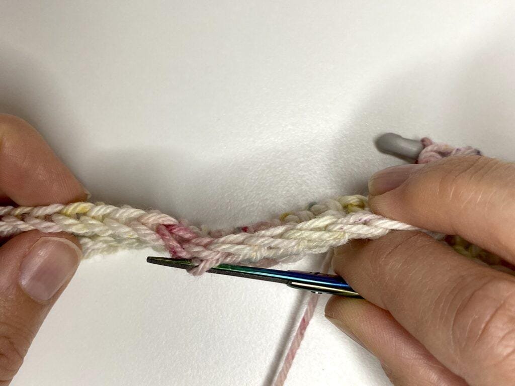 A sample of crochet viewed from the top with a pointer pointing to the third loop down the side