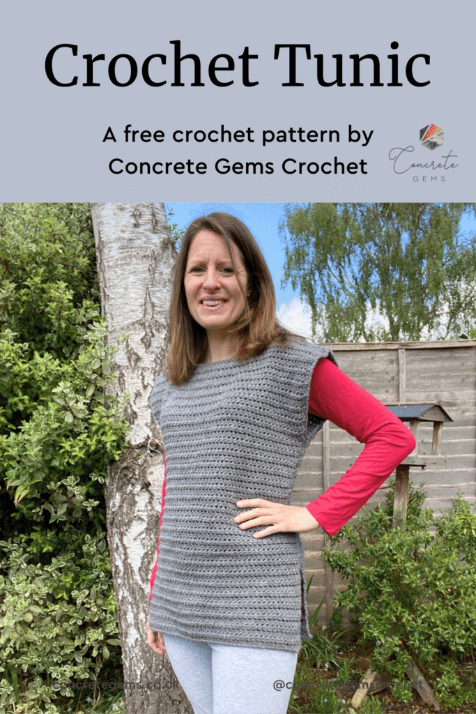 A lady stands in a sunny garden wearing a grey crochet tunic over a pink long sleeve top and leggings