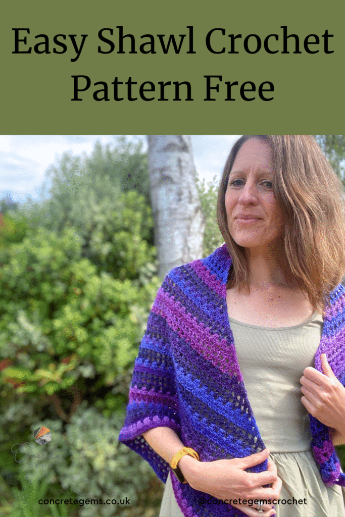 A lady stands to one side wearing a purple crochet shawl from a free pattern