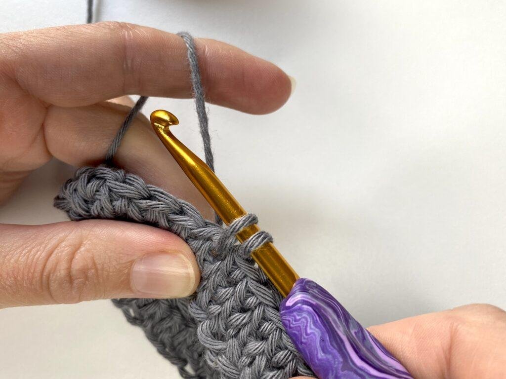 the next step of the knit stitch, pulling through a loop, is being shown here