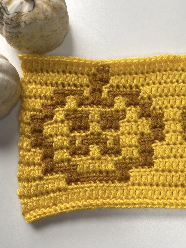 close up of a piece of mosaic crochet fabric featuring a pumpkin outline