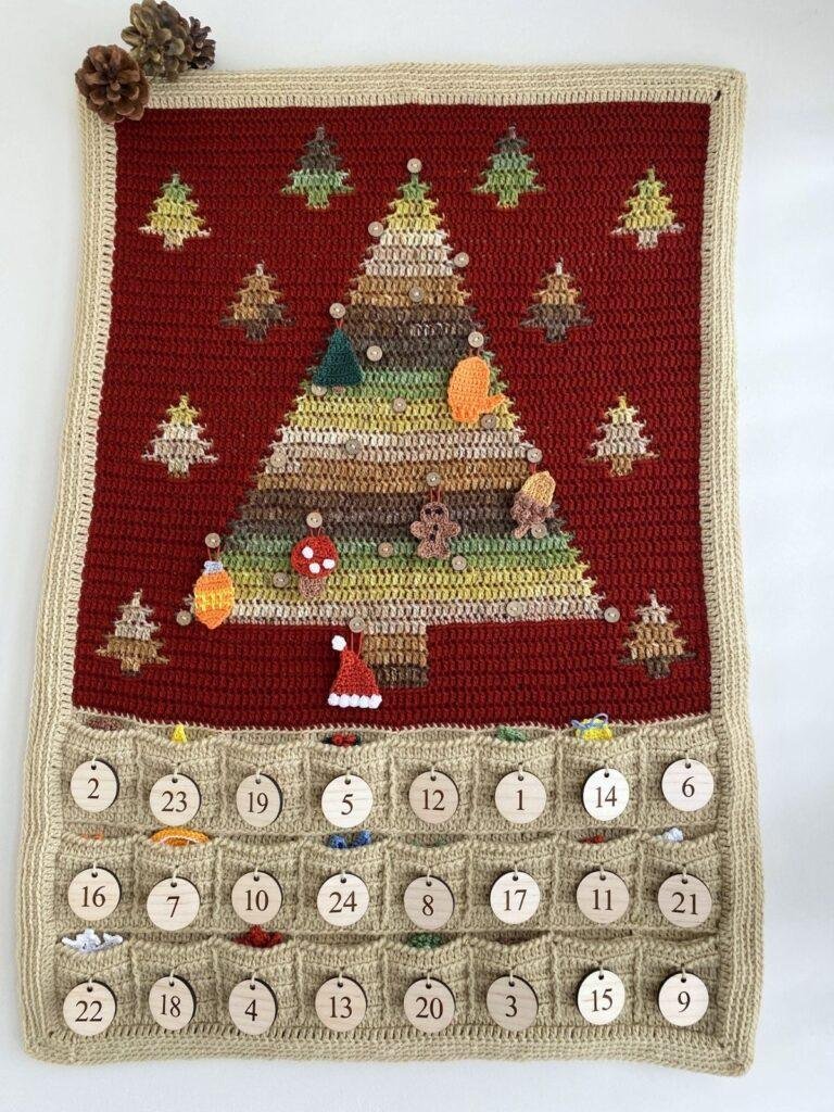 A crochet advent calendar with a Christmas tree, pockets underneath and hanging decorations on the tree