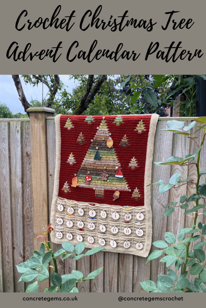 A crochet christmas tree advent calendar pattern is shown hanging on a fence with greenery around it