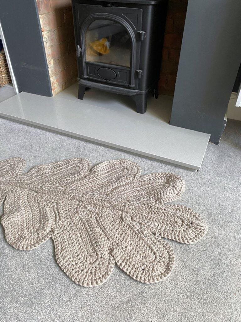 part of a grey crochet leaf rug is showing in front of a black log burner and hearth