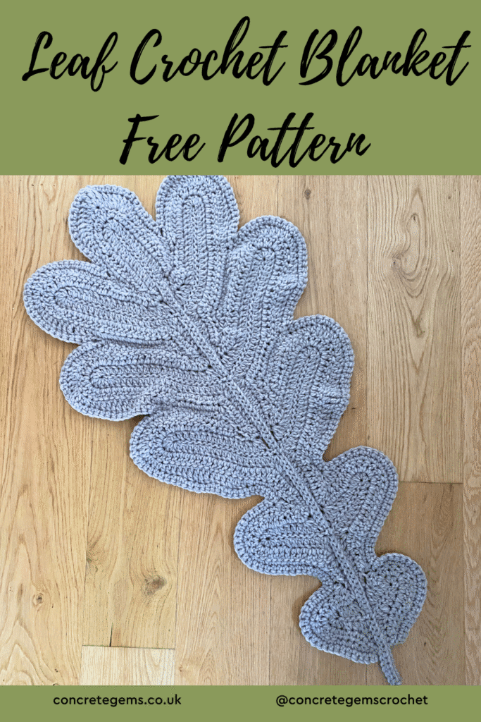 a giant grey crochet oak leaf lies on a wooden floor