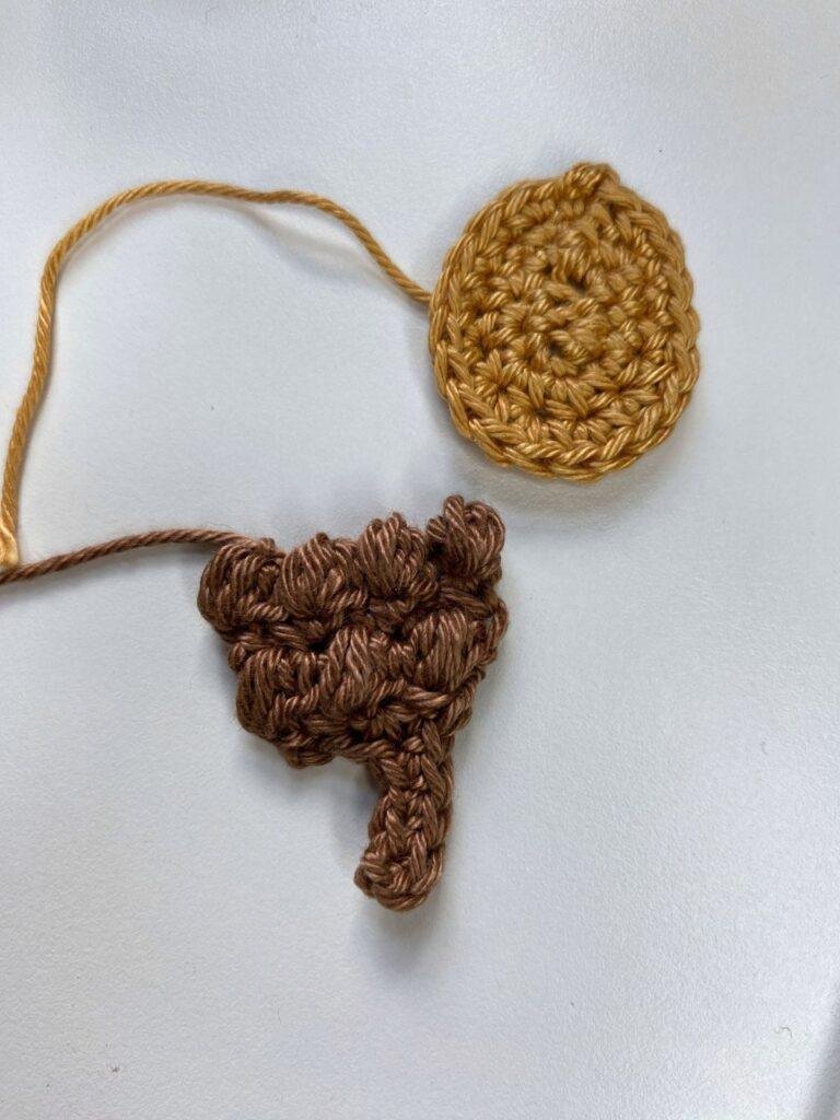 2 parts of a crochet acorn lay on a white background
