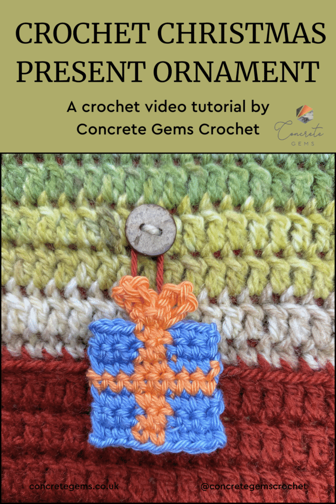 A blue crochet Christmas present ornament with an orange ribbon hangs from a button on a crochet background and the words CROCHET CHRISTMAS PRESENT ORNAMENT are above