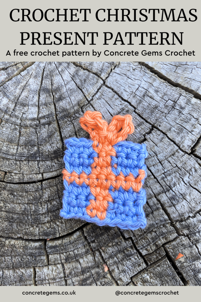 A crochet Christmas present decoration lays on a wooden slice with the words CROCHET CHRISTMAS PRESENT PATTERN above