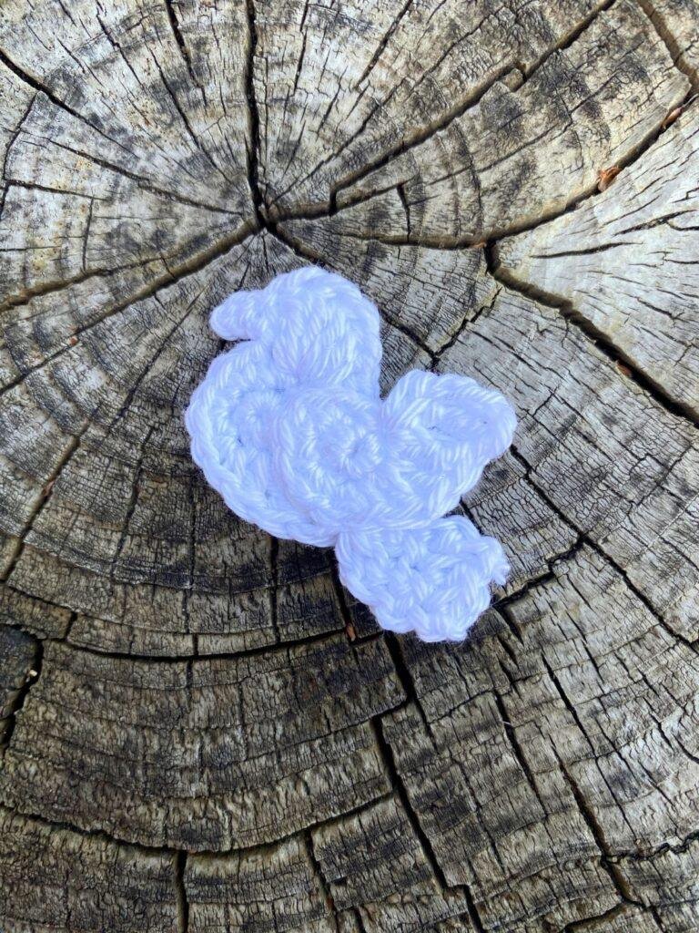 A small crochet dove appliqué sits on a wooden slice