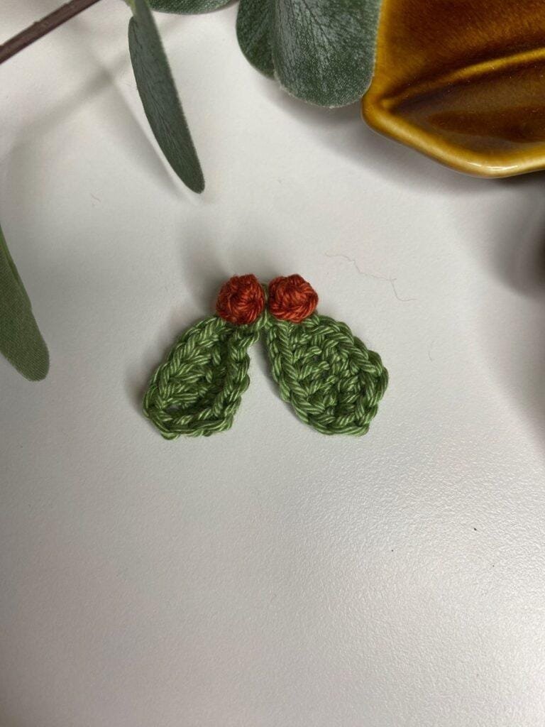 A small crochet mistletoe decoration with leaves and a leaf tray 